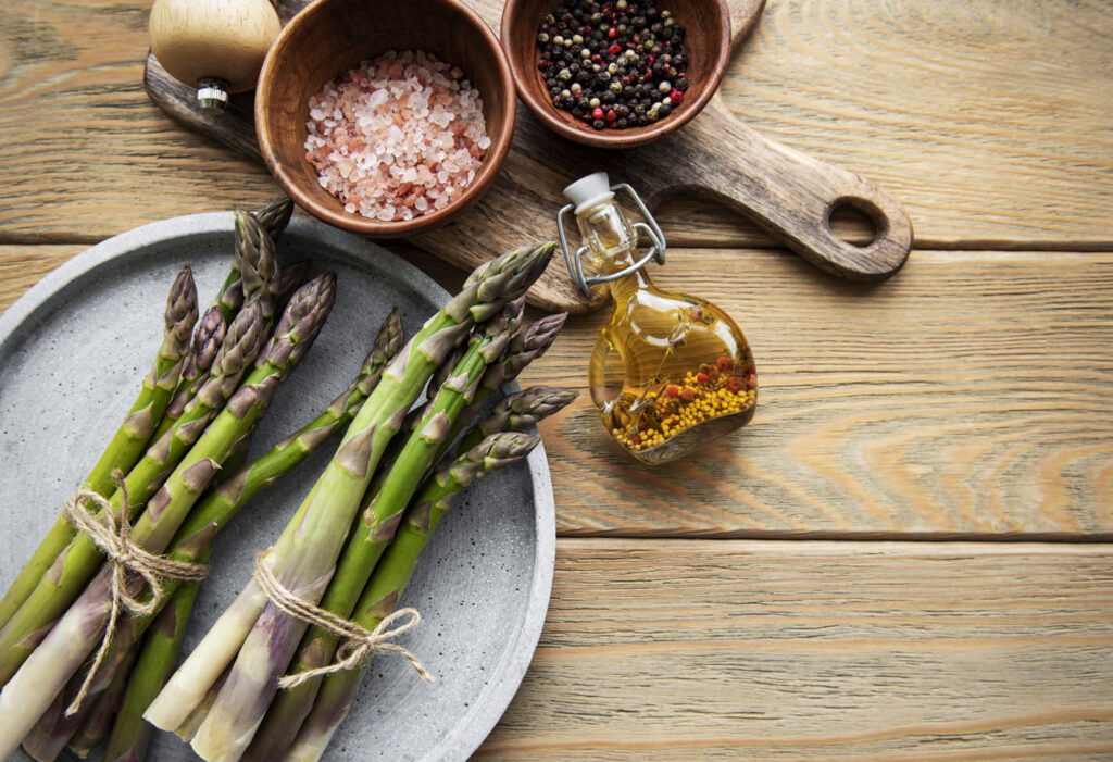 Asparagus and spices on rustic wooden background.