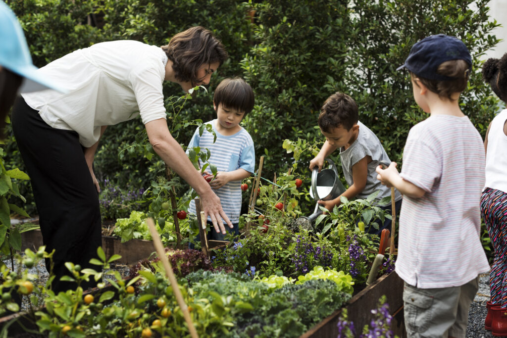 Teacher and kids embrace Blue Zone lifestyle by learning ecology and gardening, focusing on sustainable living practices.
